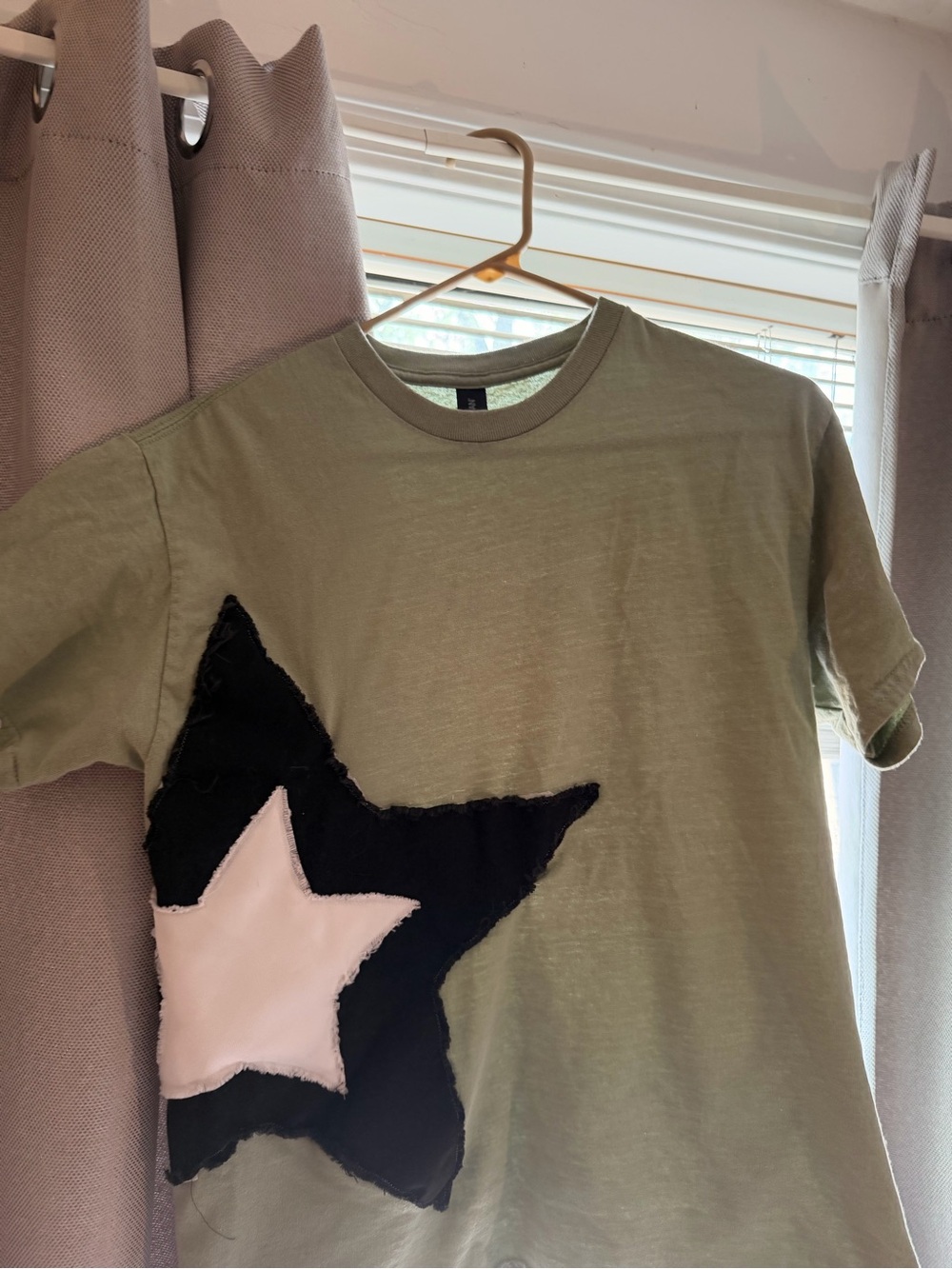 Olive green tee with a bold, off-center star design.